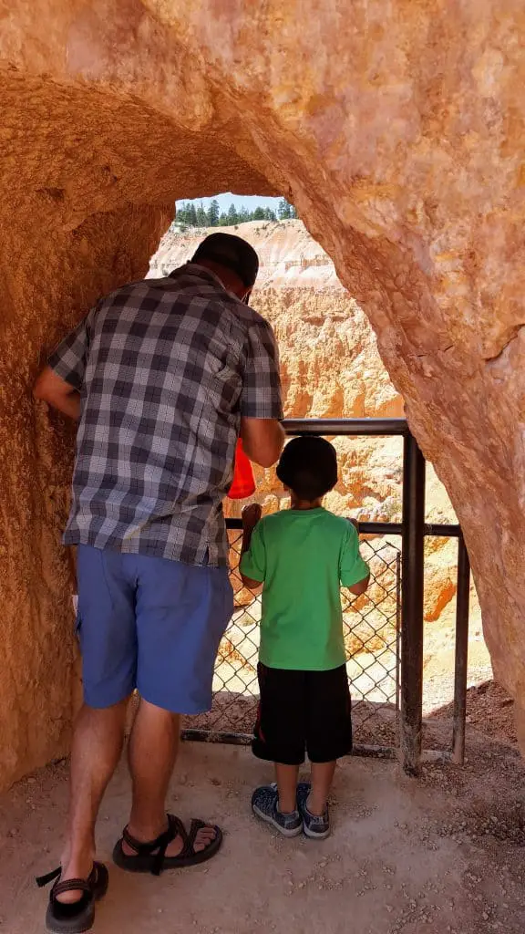 Father and son looking through a rock arch over Bryce Canyon National park