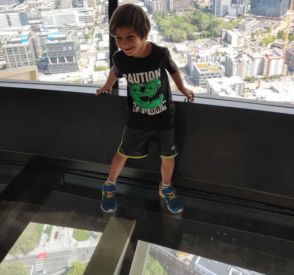 Little boy looking down through the glass floor at the top of the Space Needle in Seattle
