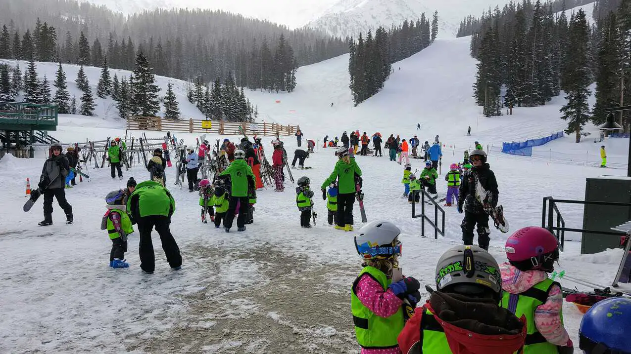 kids in a ski school class at the base of the mountain at a ski resort in Colorado