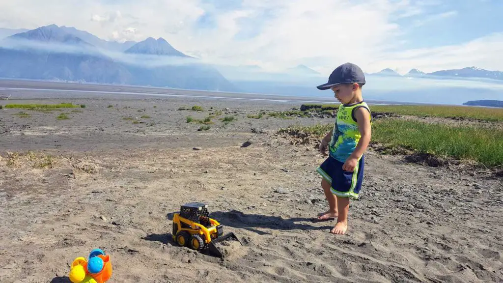 boy playing with toy trucks in the dirt in Alaska