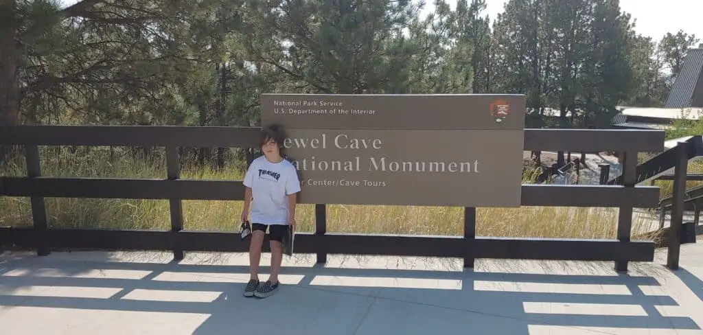 Boy standing in front of a sign for Jewel Cave National Monument