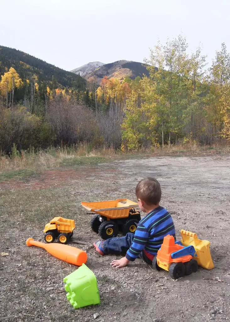 boy playing in the dirt with trucks - mountains in the background
