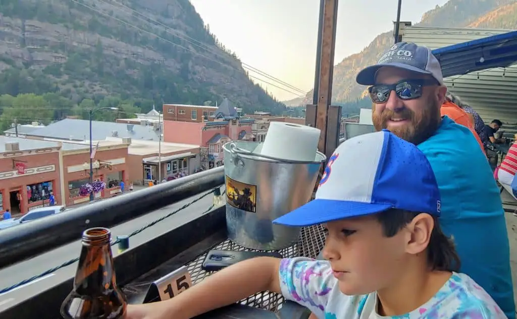 Father and son eating at Ouray Brewery on the rooftop deck - one of the fun things to do in Ouray Colorado in the summer