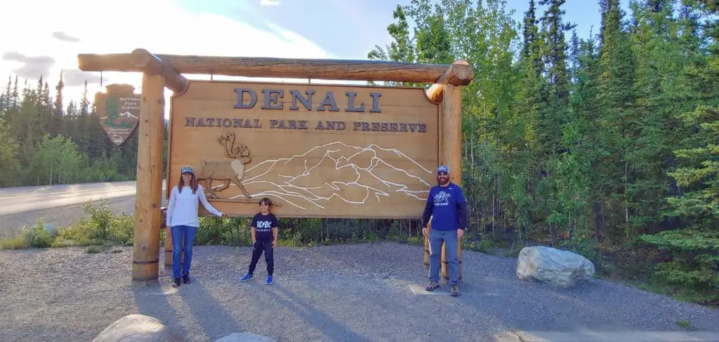 Family standing in front of the sign at the entrance to Denali National Park