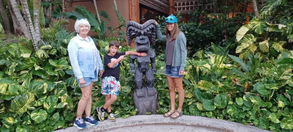 family standing in front of a statue at the Polynesian Cultural Center on Oahu, HI