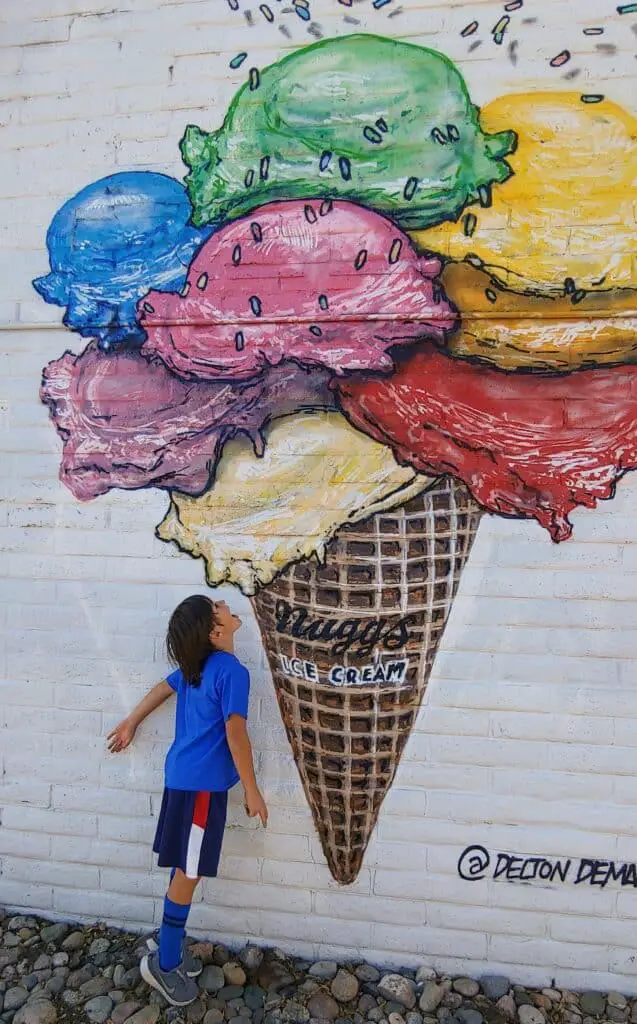 Eli pretending to eat icecream from a mural of icecream on the wall at Nuggs Ice Cream in Denver
