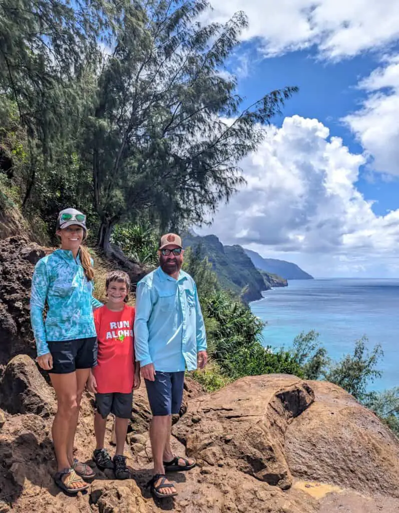 Family standing on a cliff overlooking the ocean in Hawaii