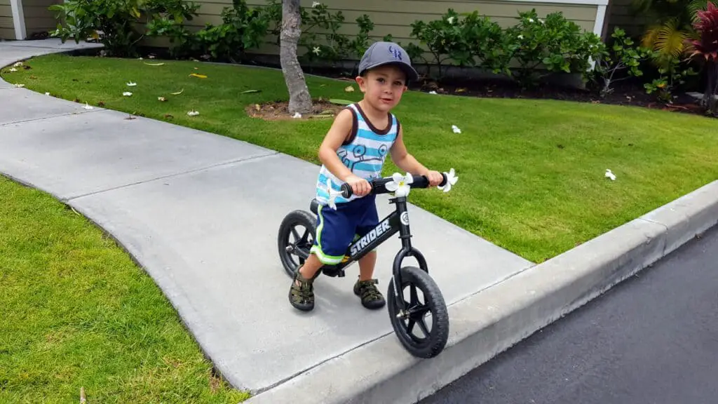 boy on a strider bike in Hawaii with Plumeria flowers on his bike